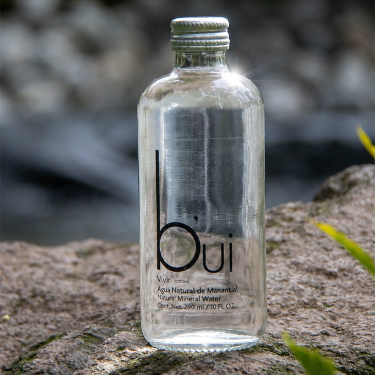 Botella b'ui sobre roca en el agua